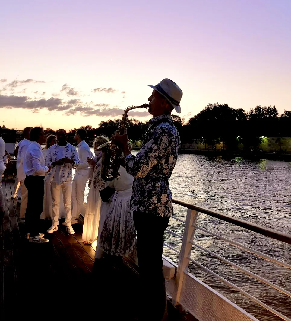 Saxophonist mikOsax playing at sunset by the water during an elegant all-white party